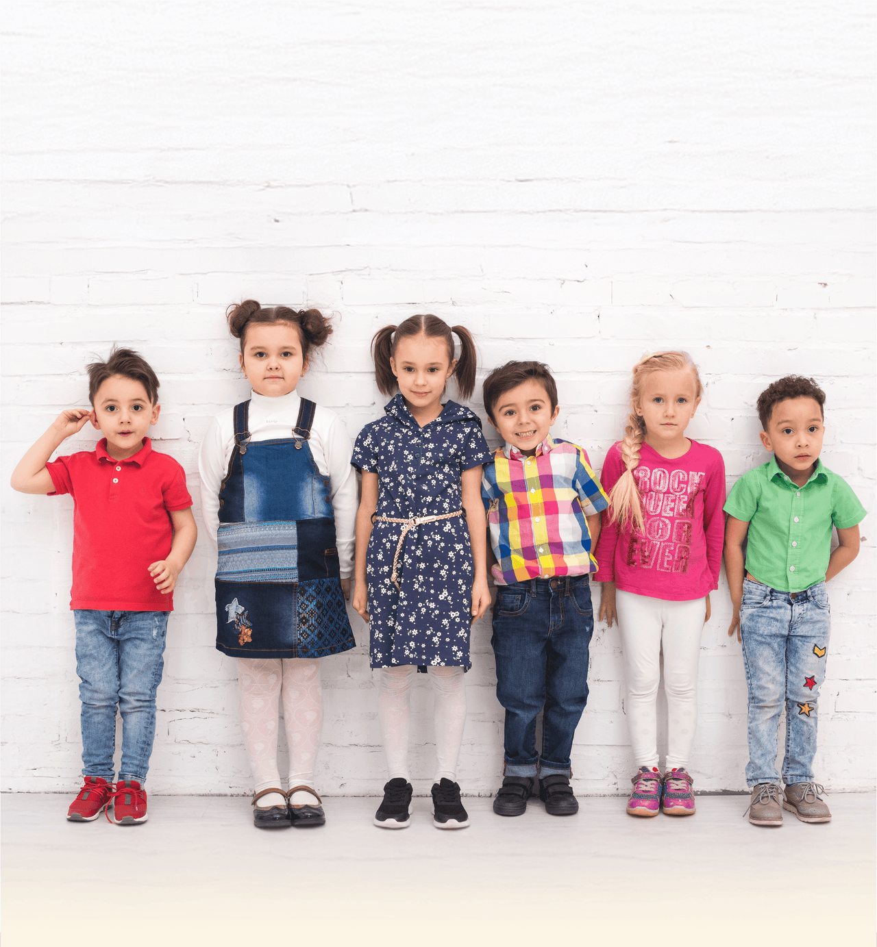 Kinder vor einer weißen Backsteinwand